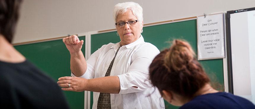 Faculty member teaching students sign language.